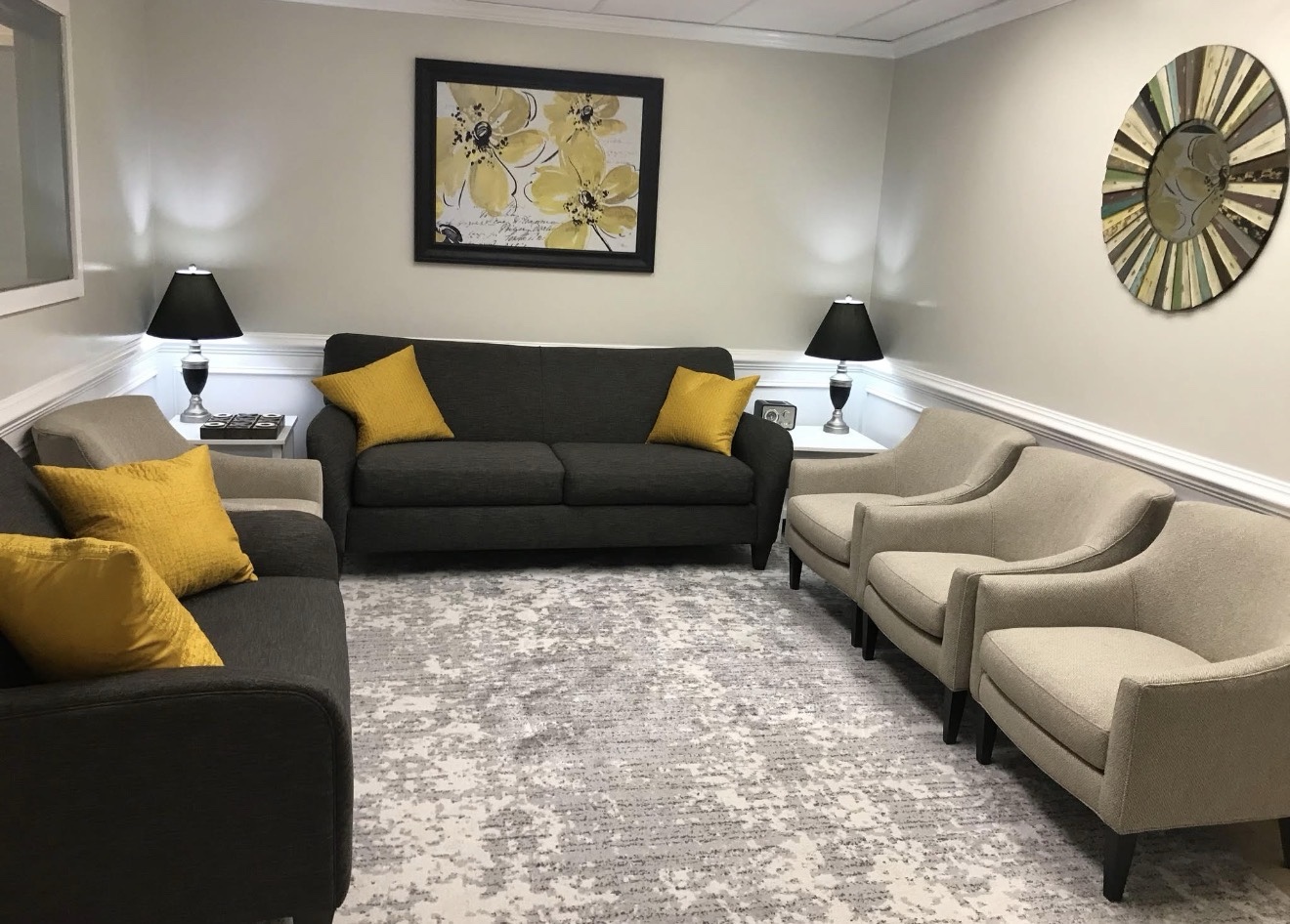 Shared waiting room with sofas, cream chairs and yellow cushions